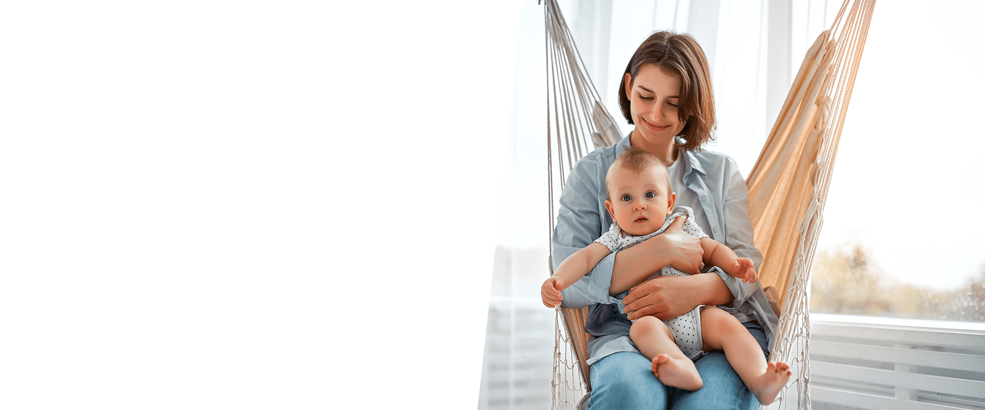 Mãe sentada em uma rede, com um bebê no colo